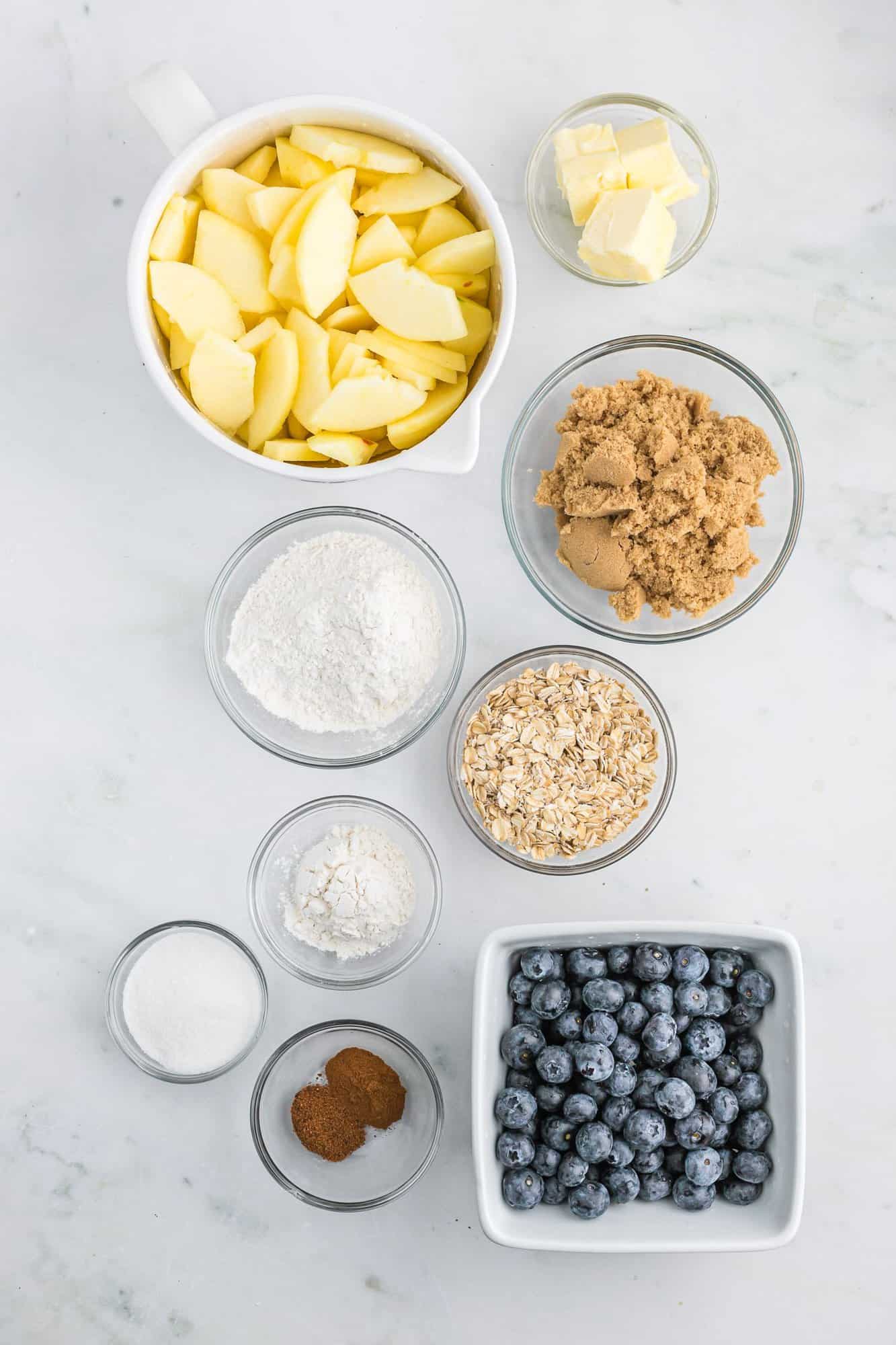 Ingredients needed in separate bowls, including apples and blueberries.