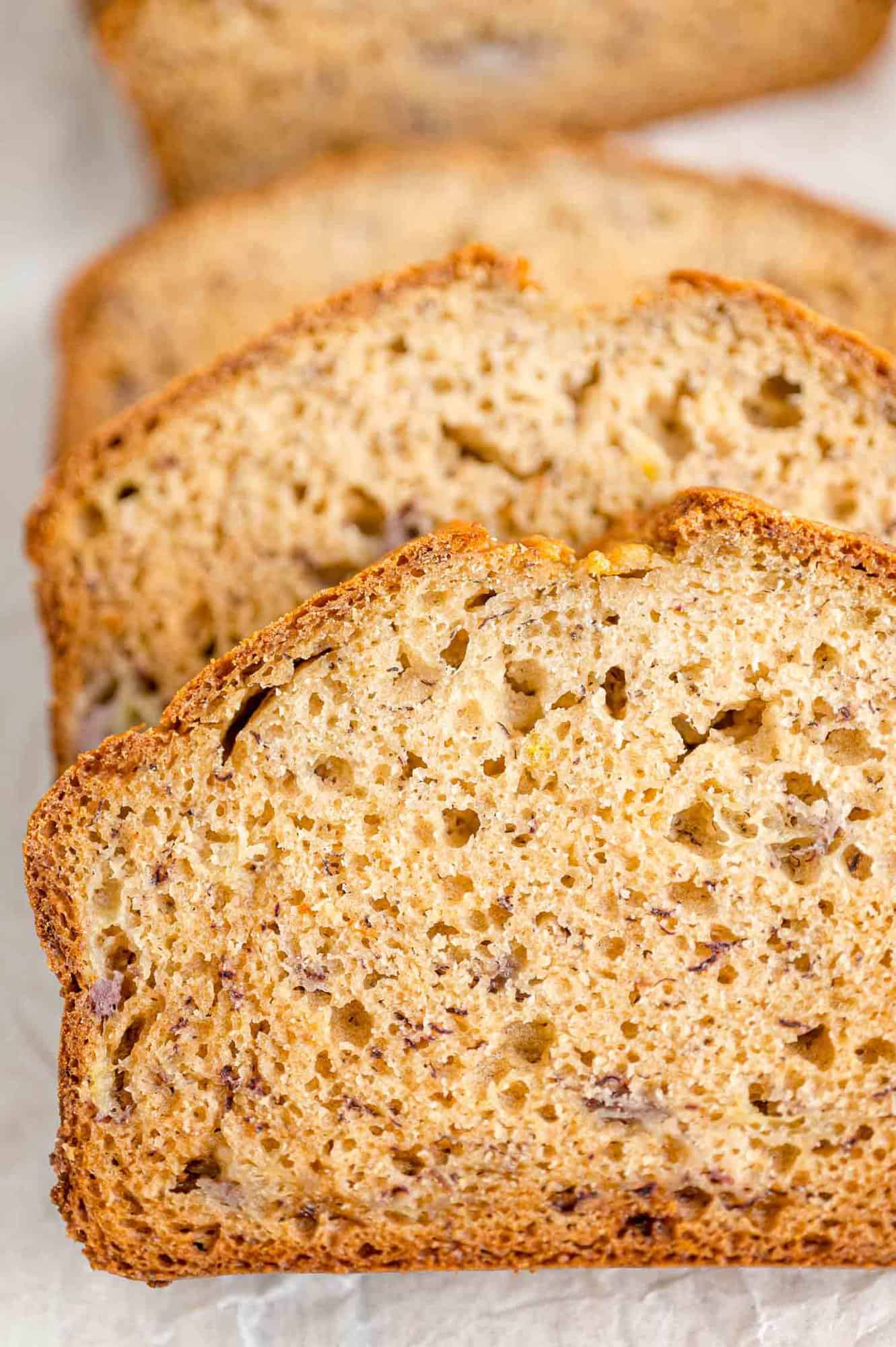 Close up of slices of banana bread on a parchment-lined cutting board.