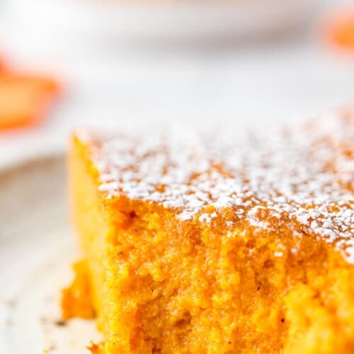 A slice of carrot souffle on a plate with a forkful missing from the corner.