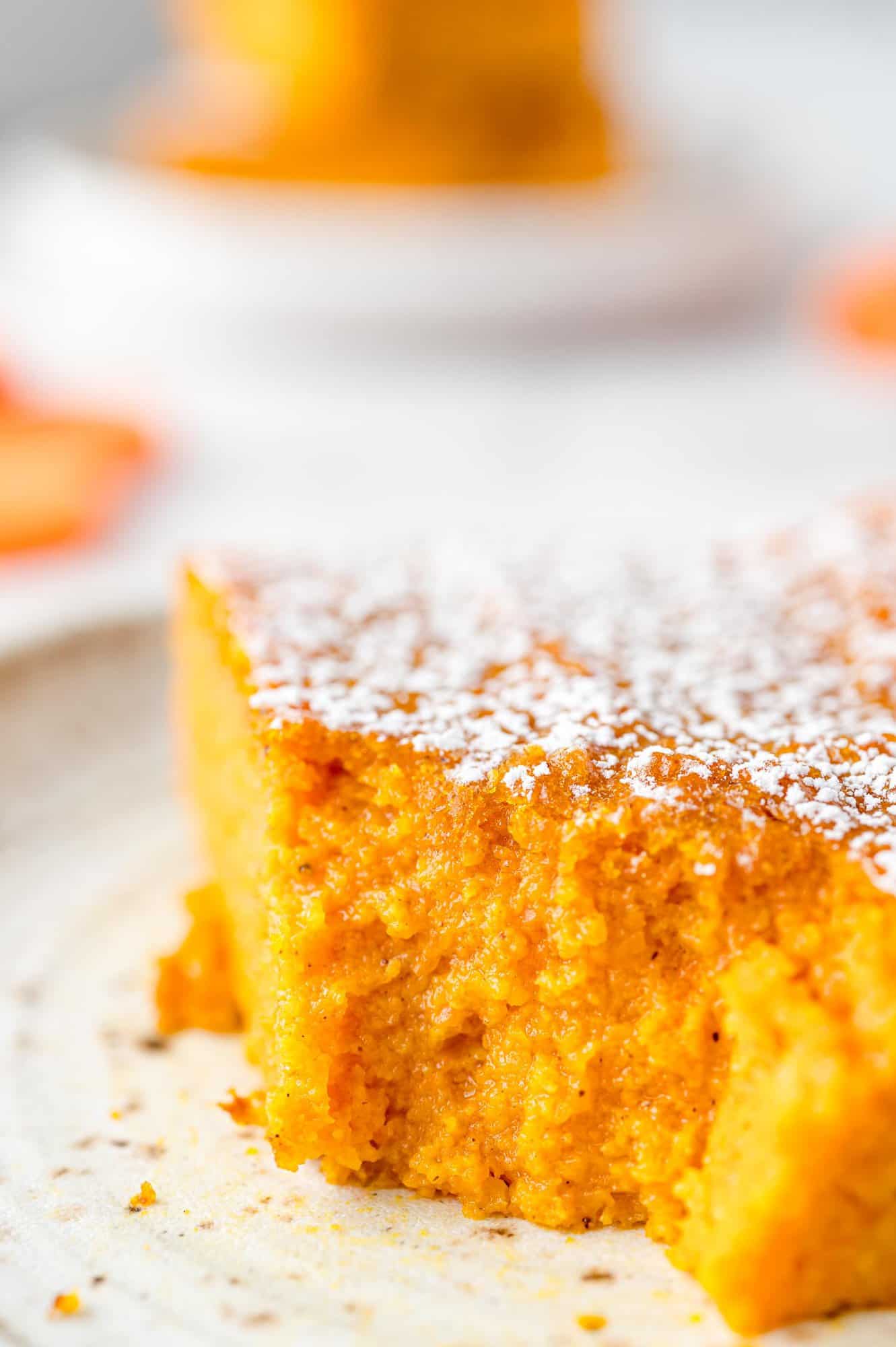 A slice of carrot souffle on a plate with a forkful missing from the corner.