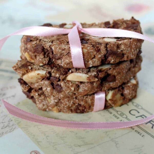 Three pieces of chocolate mocha biscotti, flecked with almonds, wrapped up with a pink ribbon.