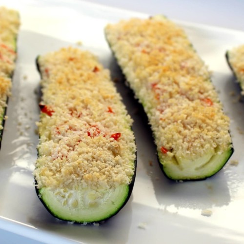 Zucchini halved lengthwise and stuffed with cream cheese and topped with breadcrumbs.