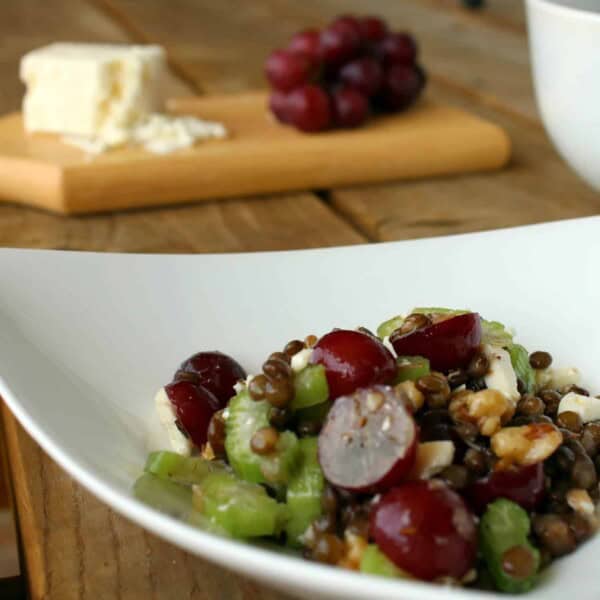 Close up view of a bowl of salad made with lentils, red grapes, celery, feta, and walnuts.