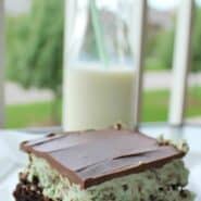 Close up view of a layered brownie - on the bottom, brownie, next green mint chocolate icing, and topped with melted chocolate.