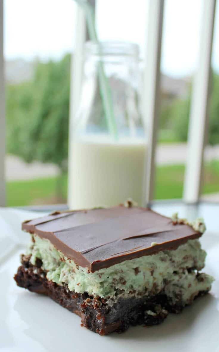 Close up view of a layered brownie - on the bottom, brownie, next green mint chocolate icing, and topped with melted chocolate.