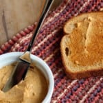 A small white bowl filled with whipped pumpkin butter next to a slice of toast and a knife.