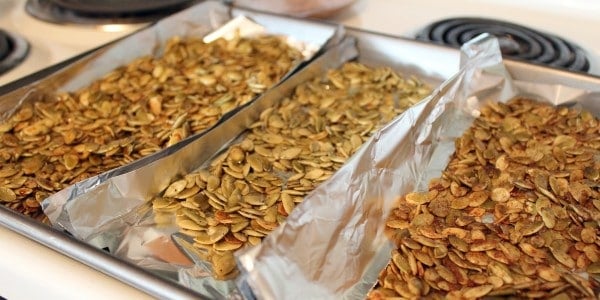 Large roasting pan, foiled lined with three types of seasoned pepitas, on stovetop.