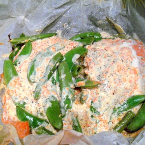 Salmon coated in sour cream with peas and carrots.