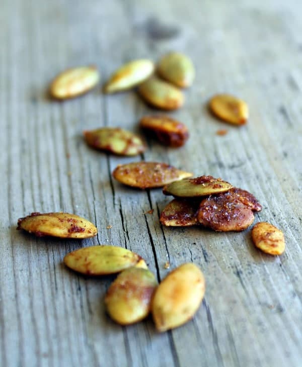 Several seasoned roasted pepitas on gray board.