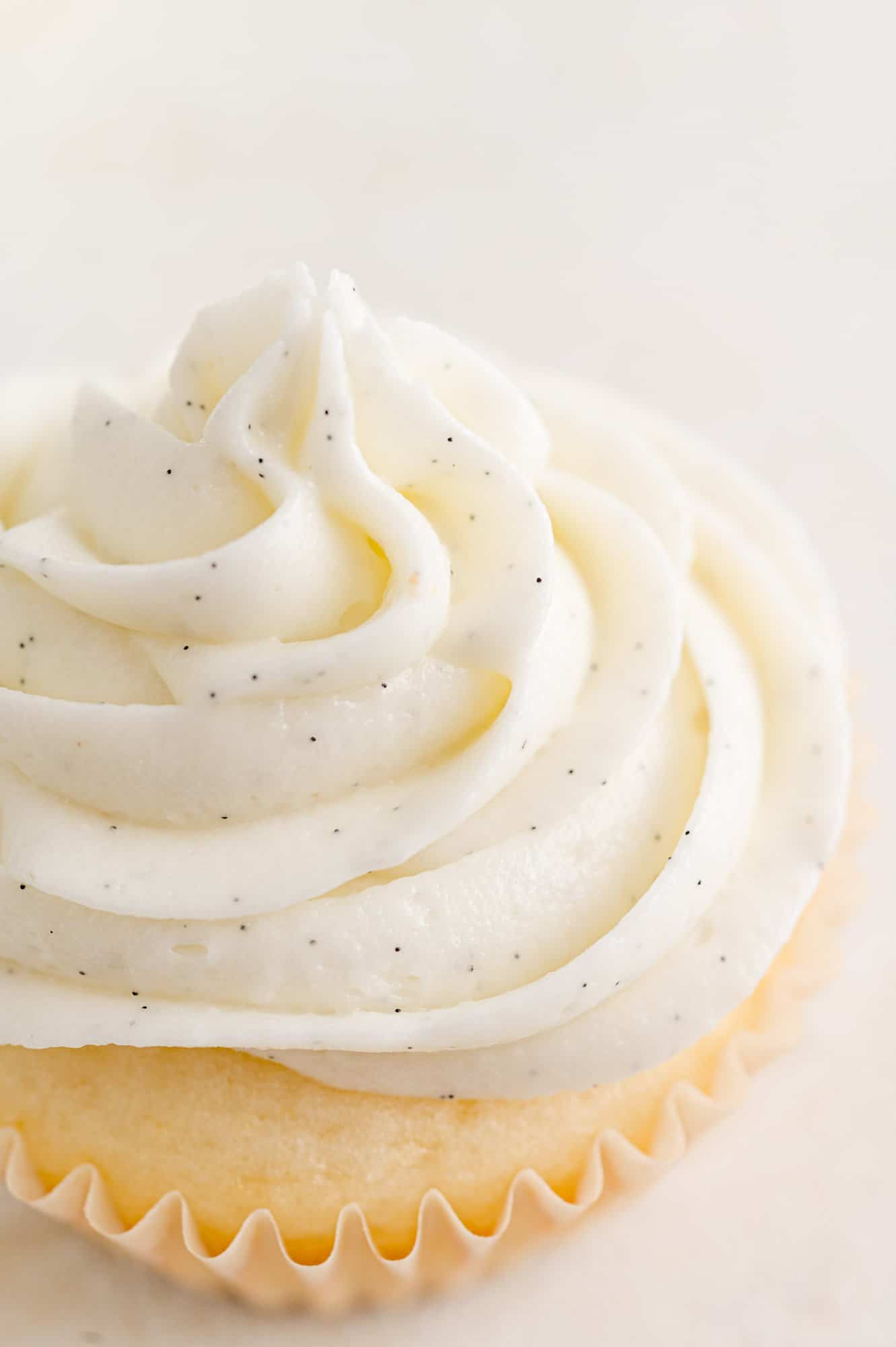 Close up of a vanilla cupcake topped with a swirl of vanilla buttercream frosting.