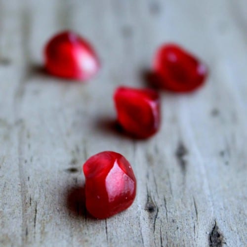 Pomegranate seeds on wooden background.