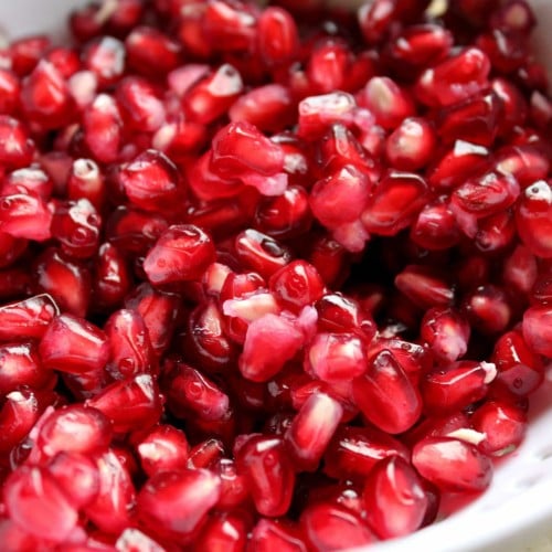 Pomegranate arils in a white strainer.