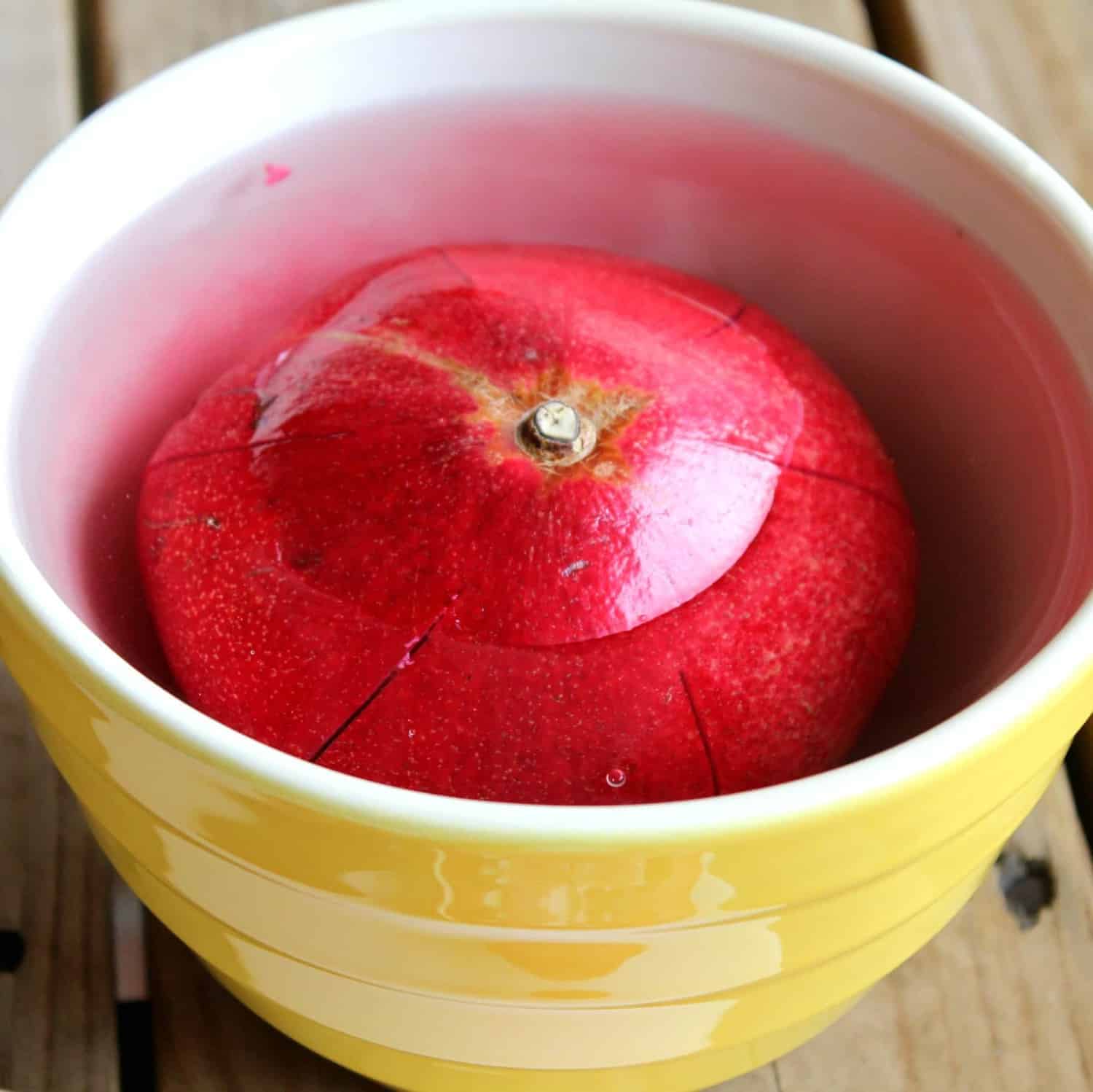 Pomegranate face down in a bowl of water.