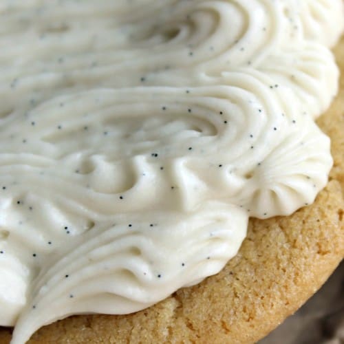 Very close up view of vanilla frosting on a sugar cookie to show lots of vanilla bean flecks.
