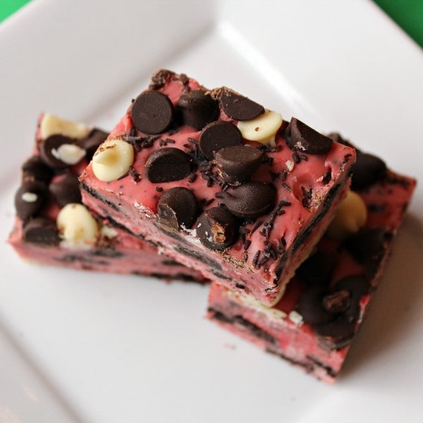 Overhead view of pink fudge with chocolate and white chocolate chips on a white plate.