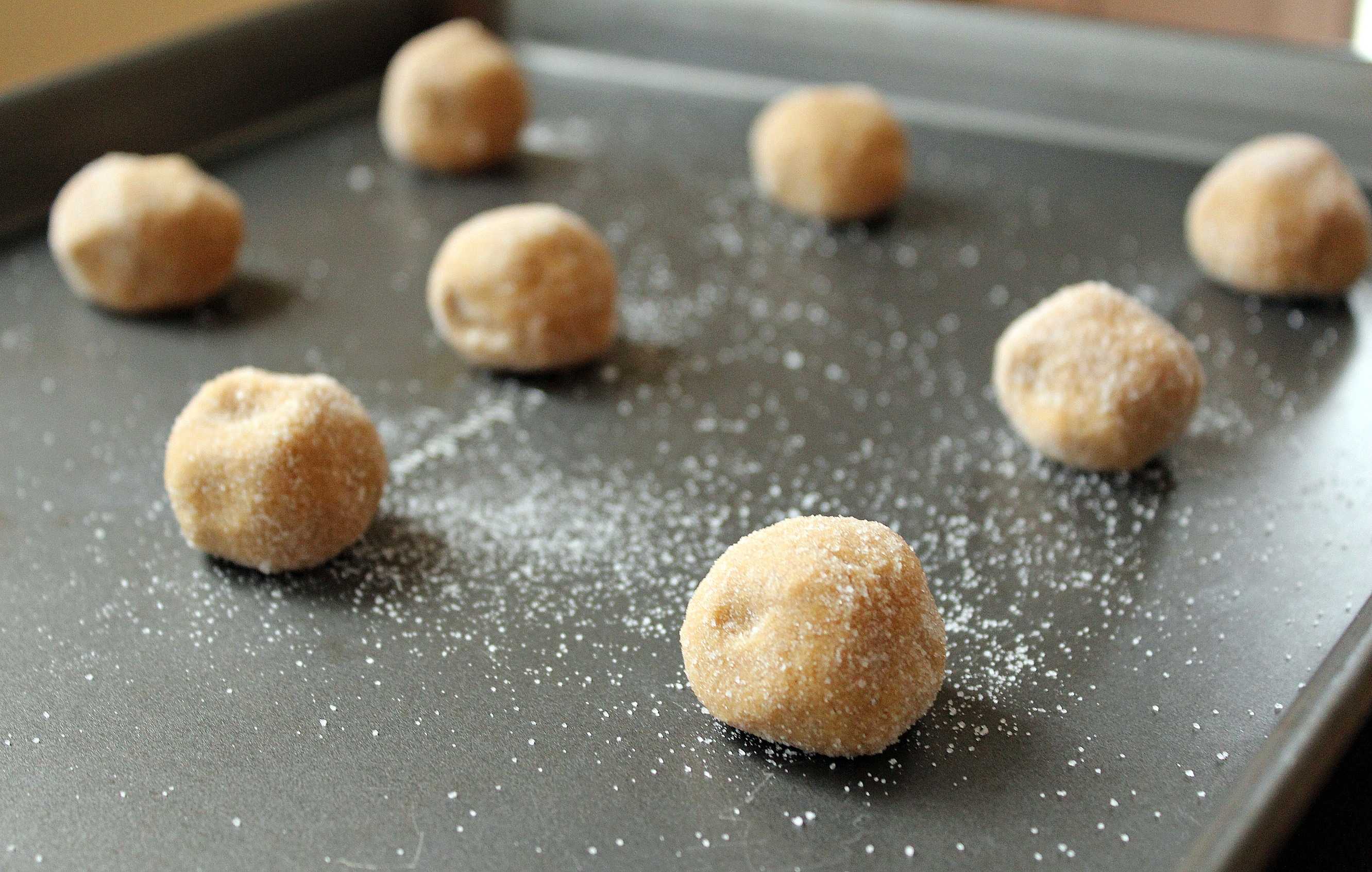 Cookie dough rolled into balls and rolled in granulated sugar, placed on a cookie sheet. 