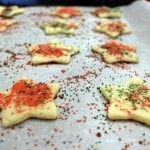 Cut out cookies in the shape of stars sprinkled with red and green sugar on cookie sheet.