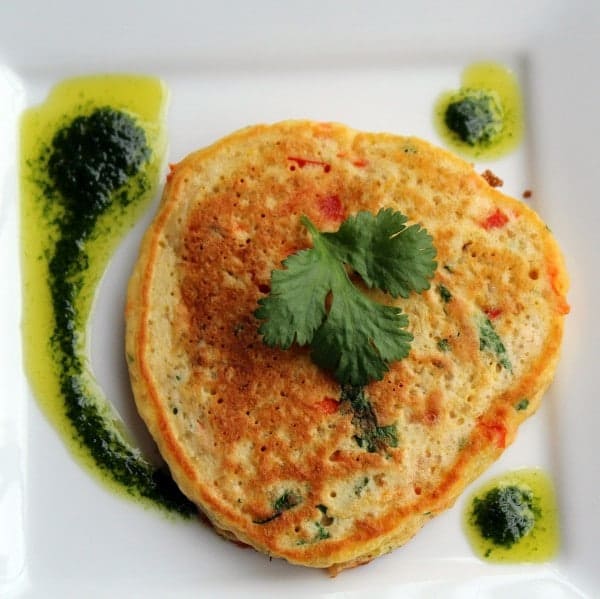 Overhead of pancake with vinaigrette on square white plate.