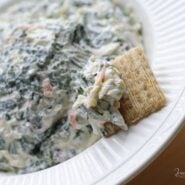 Partial view of spinach dip in bowl with cracker.