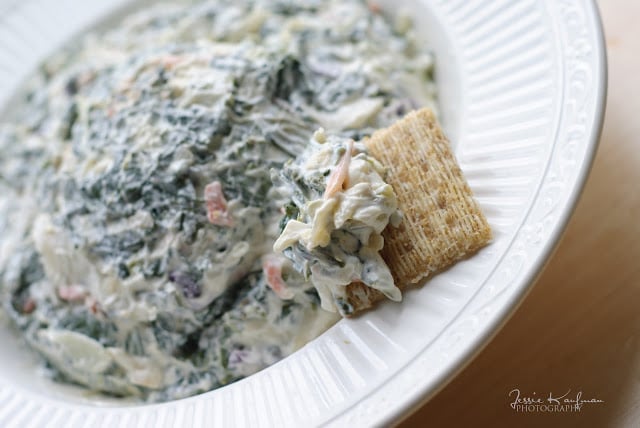 Partial view of spinach dip in bowl with cracker.