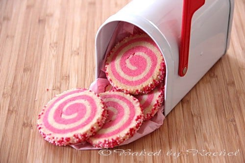 Pink and white spiral patterned sugar cookies coming out of a white mailbox.