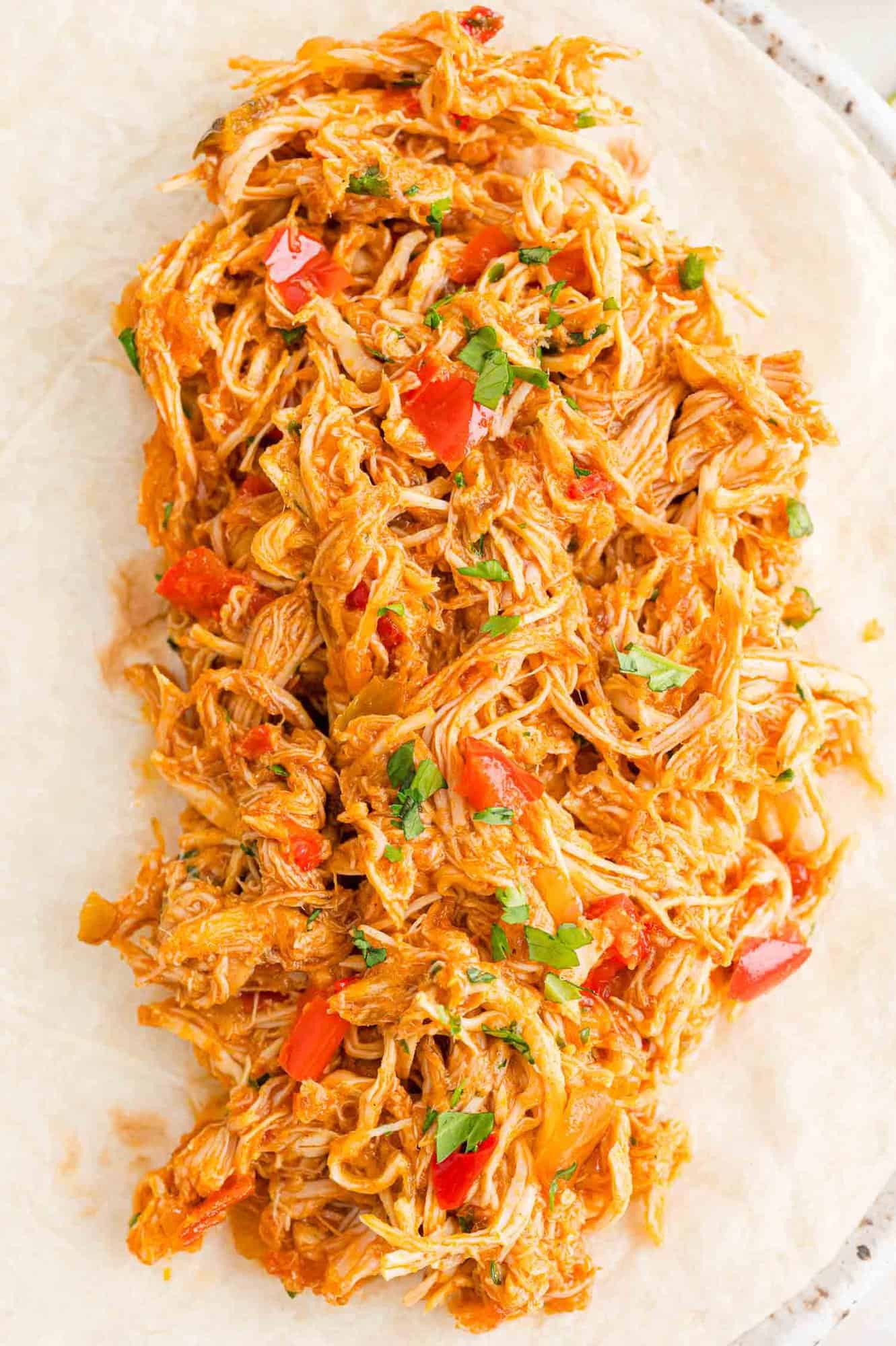 Overhead view of a large flour tortilla topped with crockpot salsa chicken.