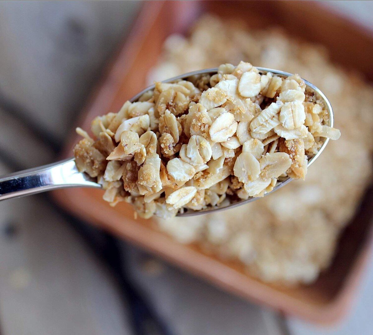 Overhead closeup of spoonful of granola, with bowl in background.