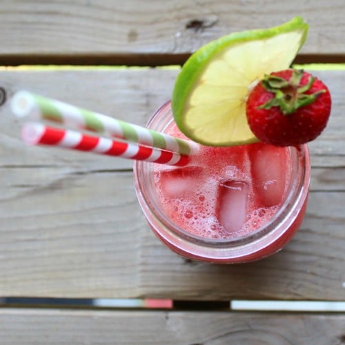 Overhead view of strawberry watermelon slushie garnished with slice of lime and strawberry.