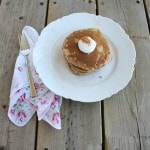 Pancakes on a white plate on a wooden surface.