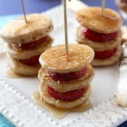Three stacks of pancakes on skewers, layered with strawberries.
