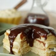 Stack of pancakes, with wedge removed, on square silver plate.