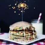 A stack of pancakes topped with lit sparkler.
