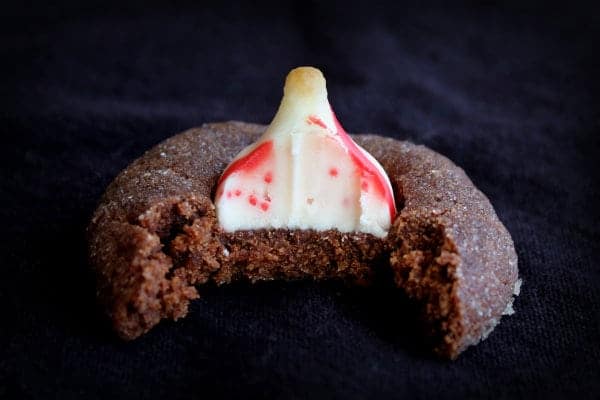 Closeup of one cookie, bitten in half, on black background.