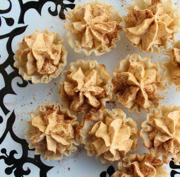 Overhead view of mini pumpkin pie tarts on a countertop.