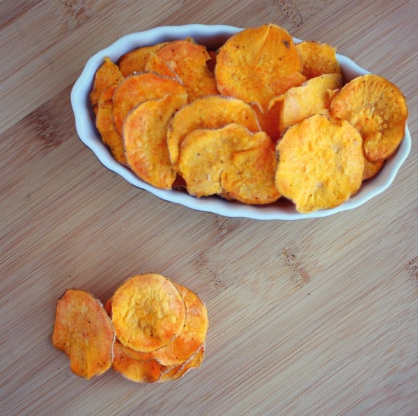 Overhead of sweet potato chips in oval bowl, with a small stack alongside.