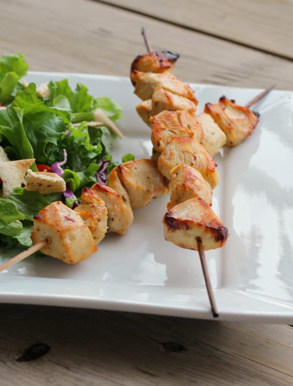 Skewers with chicken on plate with salad.