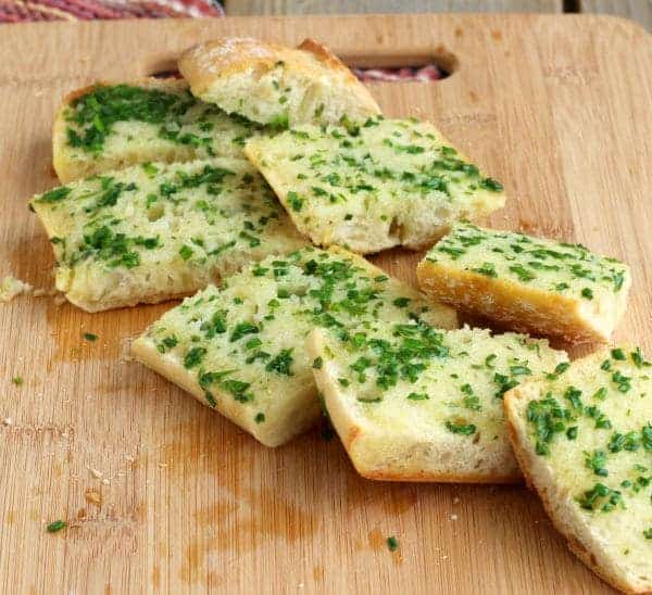 Front view of sliced chive hread on a wooden cutting board.