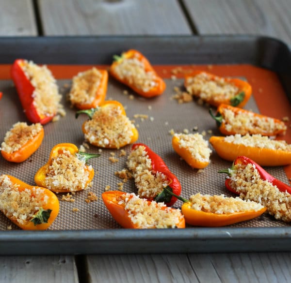 Front view of stuffed peppers on silpat baking mat in baking pan.