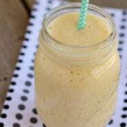 Front/overhead view of smoothie with green striped straw in jar, on black polka dots cloth.