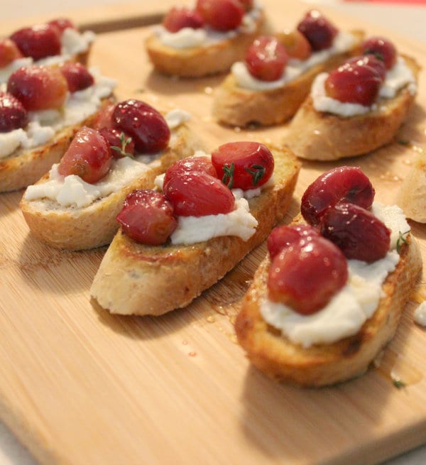 Image of roasted grape crostini on a wooden board. 