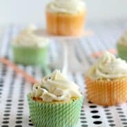 Front view of several frosted vanilla cupcakes on a black and white polka dot cloth.