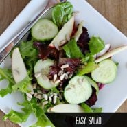 Overhead view of tossed green salad on a plate. Text overlay reads "easy salad with cucumbers and apples"