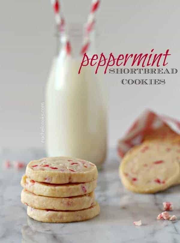 Front view of a stack of four cookies on a white marble surface, with more cookies in background and bottle of white milk with red and white straws. Text overlay reads "peppermint shortbread cookies."