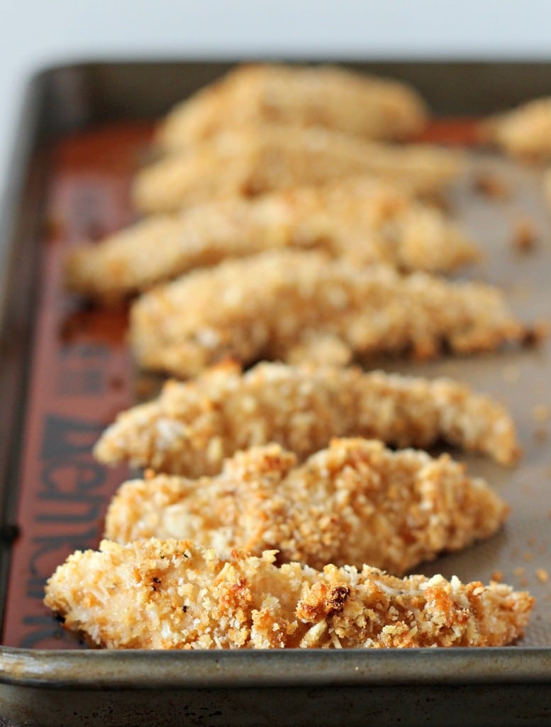 Several baked chicken tenders in sheet pan lined with silpat.