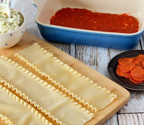 Cooked lasagna noodles laid out on a wooden cutting board.