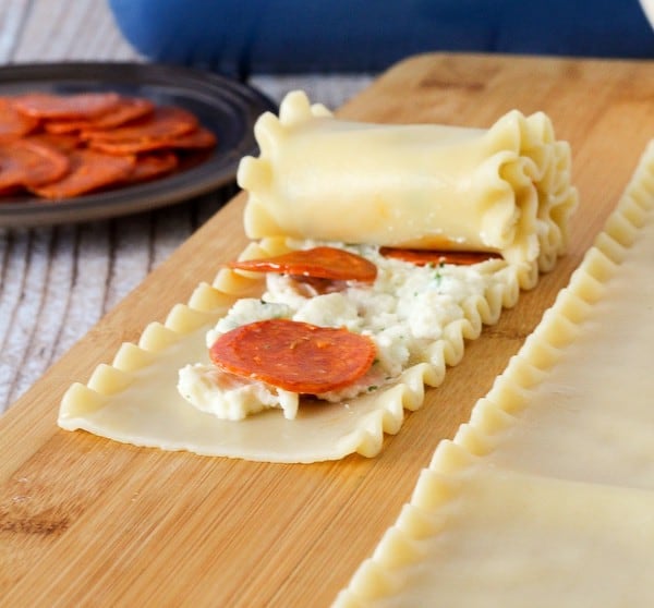 Pepperoni pizza roll being rolled up.