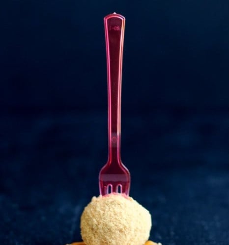 One cheesecake ball with red plastic fork inserted upright.