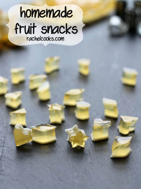Fruit snacks in various shapes scattered on grey background. Text overlay reads "homemade fruit snacks, rachelcooks.com".