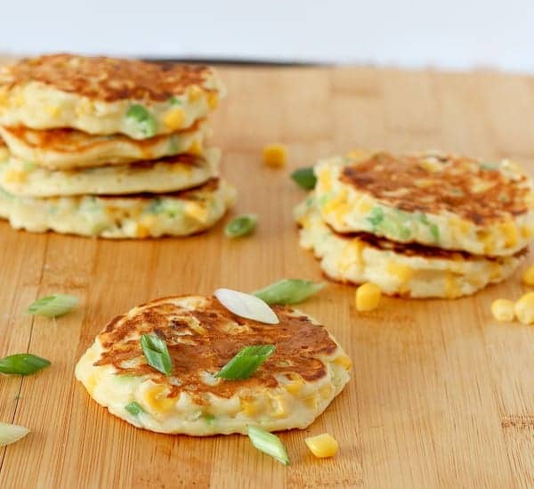 Several corn cakes on wooden cutting board.