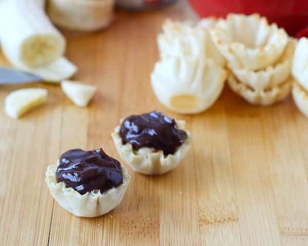 Two pastry cups filled with chocolate pudding.